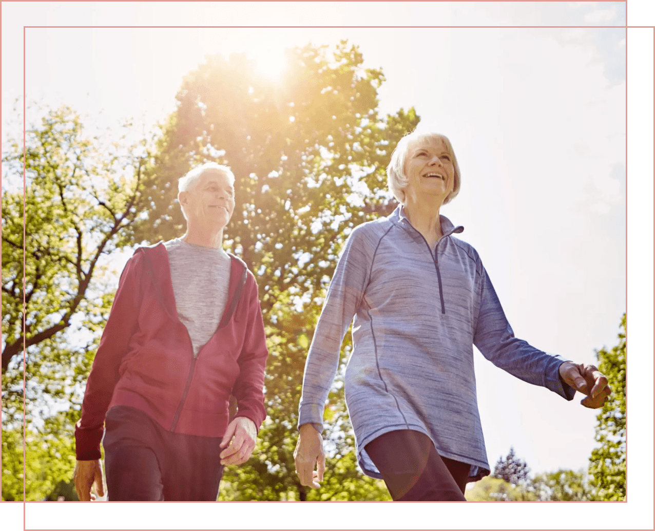Two elderly women walking outdoors in sunlight.