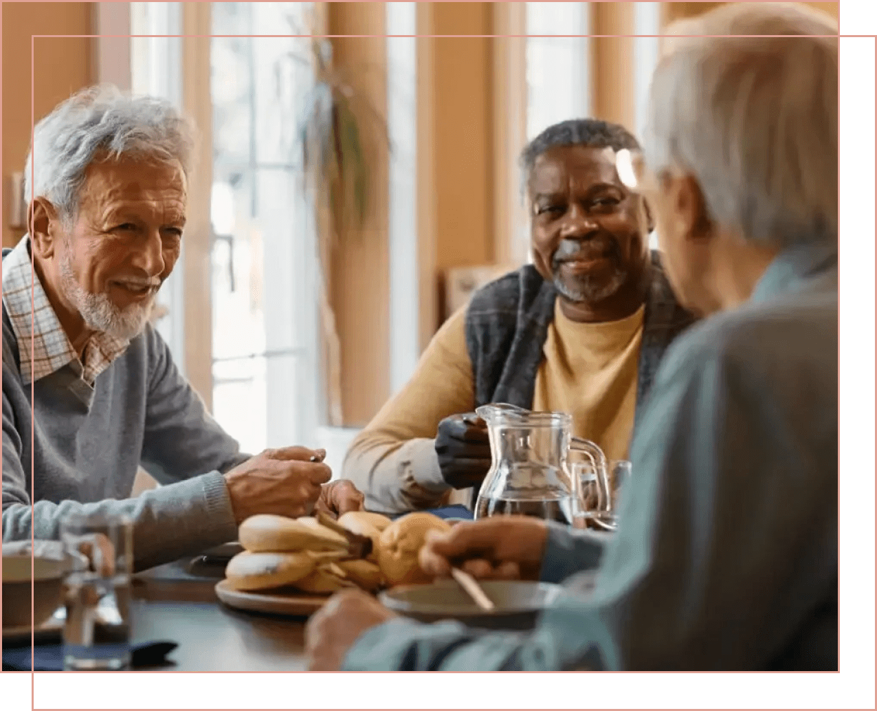Three elderly men enjoying coffee and conversation indoors.