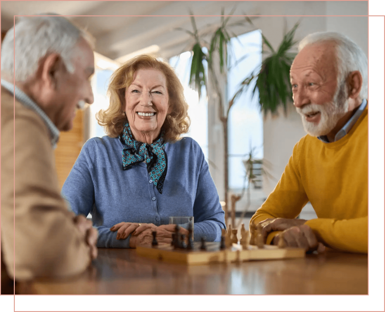 Three elderly friends enjoy playing chess together indoors.