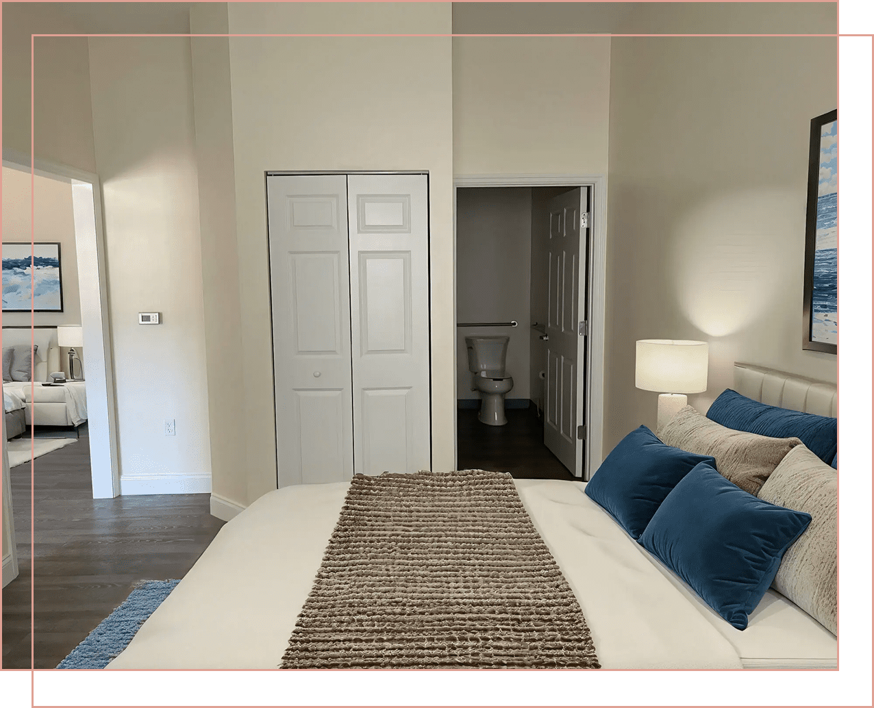 Cozy bedroom with a bed, blue pillows, and a bathroom visible through an open door.